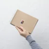 Hand holding notebook with American flag sticker.