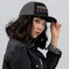Woman in black denim jacket wearing a "Pissed Redneck" hat.